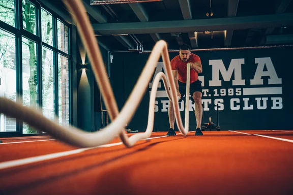 Männliche Person in Sportkleidung, die zwei Seile schwingt 