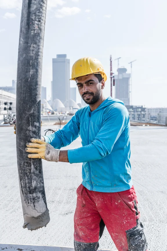 Arbeiter mit Helm, der einen Betonschlauch hält