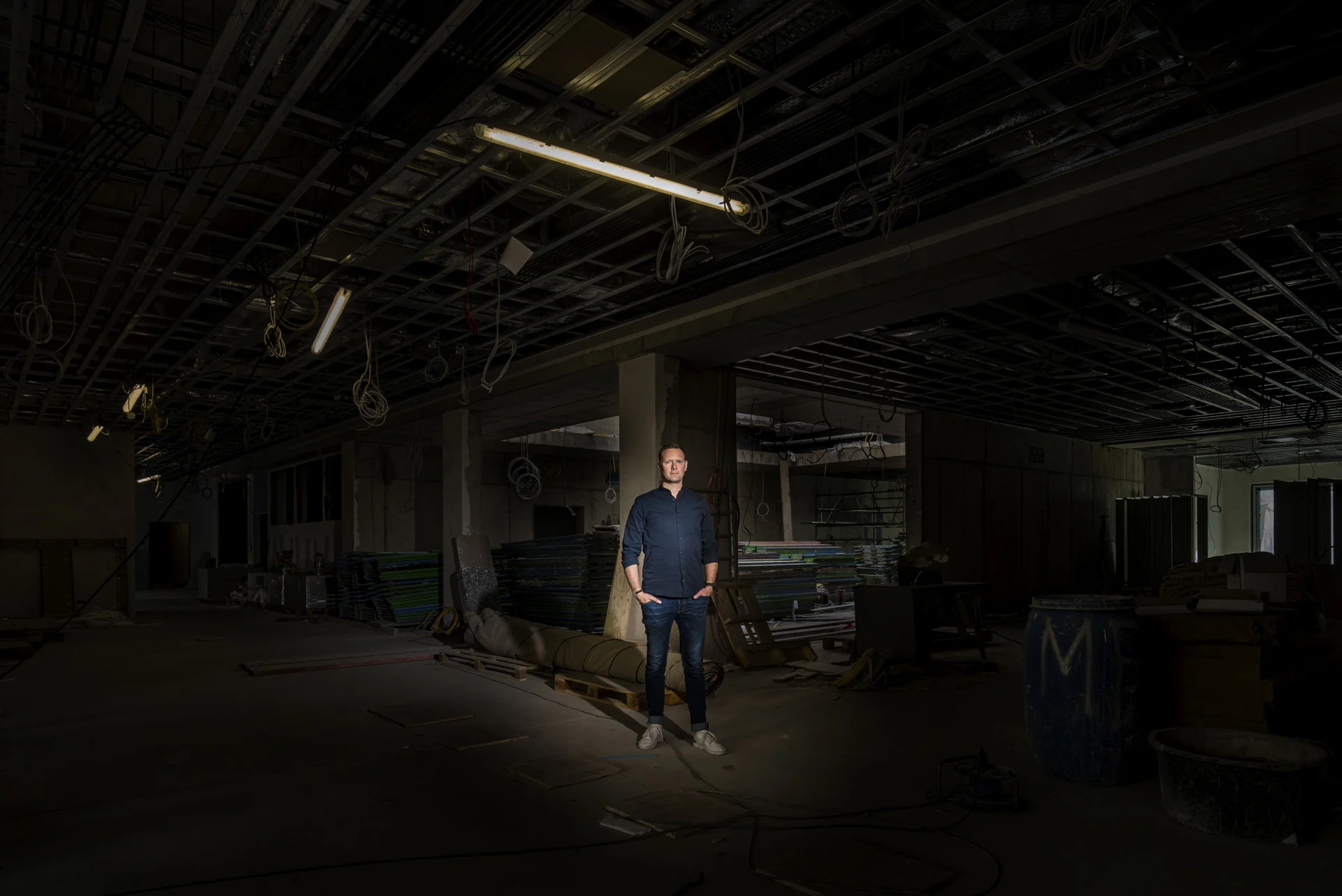 Lichtspot auf Person in der mitte einer Menschenleeren Lagerhalle