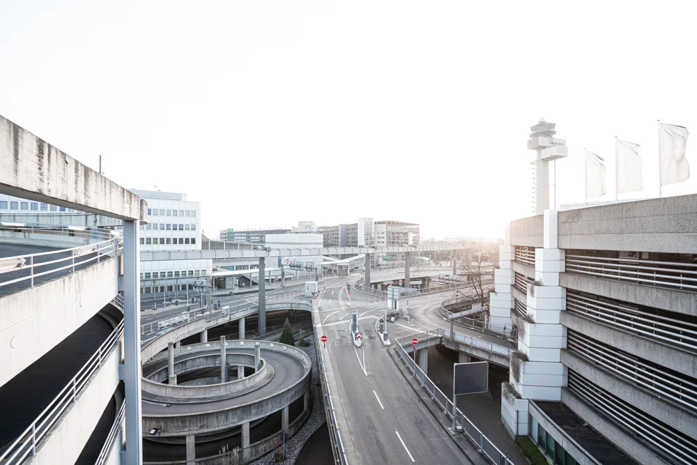 Straßengebilde mit Parkhaus links und Gebäuden im Hintergrund